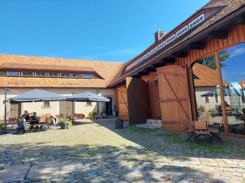 a building with tables and umbrellas in front of it at Familien- und Apartmenthotel Lerchenberghof in Kottmar