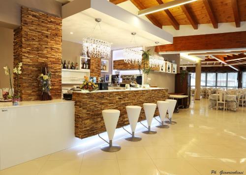 a restaurant with a bar with white stools at Villa Clorè Hotel & Spa in Lama Mocogno