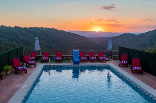 a pool with chairs and a sunset in the mountains at 21 Sleeps Private Pool Villa & BBQ Near Barcelona in Rocafort