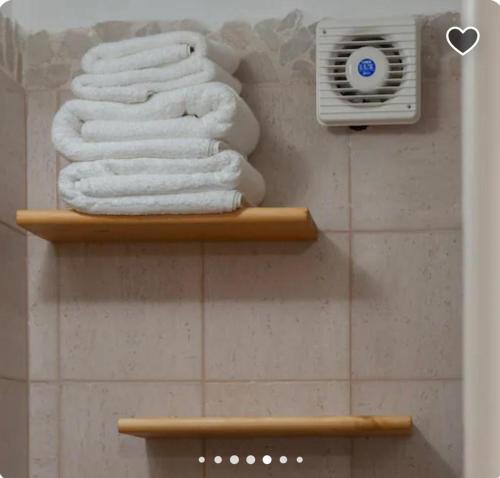 a bathroom with two shelves with towels and a heater at una volta al centro via roccamara in Nardò