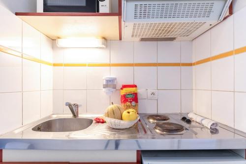 - un comptoir de cuisine avec un évier et un bol de fruits dans l'établissement Zenitude Hôtel-Résidences Le Havre, au Havre