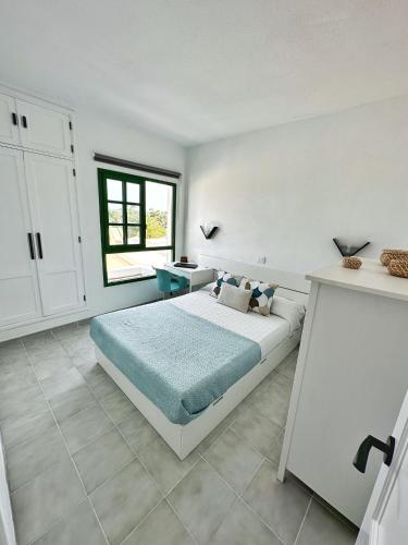 a white bedroom with a bed and a desk at Bungalow Yaipe in Maspalomas