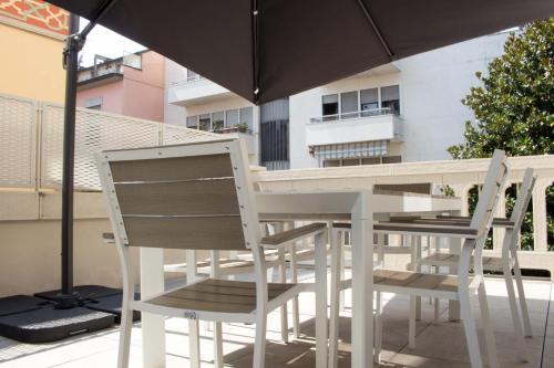 2 sillas y una mesa con sombrilla en el balcón en AR Prestige Penthouse - Noho, en Bérgamo