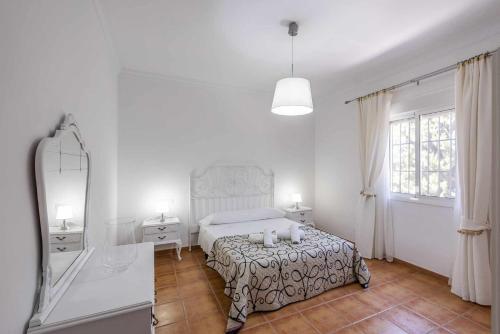 - une chambre blanche avec un lit et un miroir dans l'établissement Casa Rural Manuel, à La Puebla de Cazalla