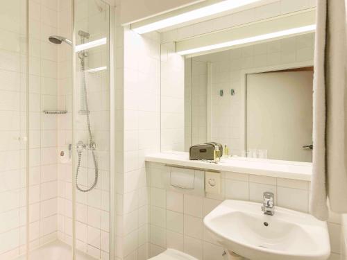 a white bathroom with a sink and a shower at Ibis Wien Messe in Vienna