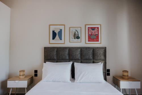 a bedroom with a bed with white pillows and pictures on the wall at Pearl Apartel in Volos