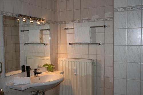 uma casa de banho com um lavatório e um chuveiro com um espelho. em Atrium Hotel em Crimmitschau