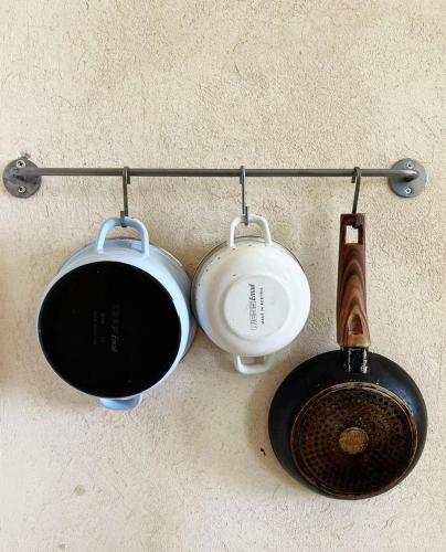 three pots and pans hanging on a wall at Benichuta in Mitzpe Hila