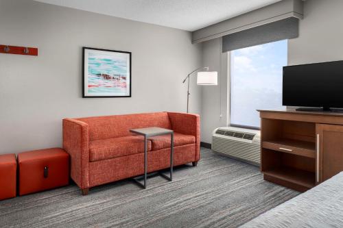 a hotel room with a couch and a television at Hampton Inn & Suites at Lake Mary Colonial Townpark in Lake Mary