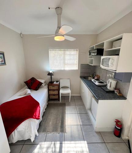 a small bedroom with a bed and a kitchen at Sundune Guest House in Colchester