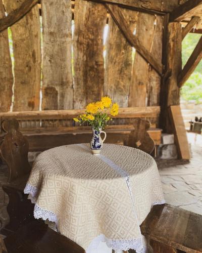 a table with a vase with yellow flowers on it at Castle View Saschiz - Traditional Guesthouse in Saschiz