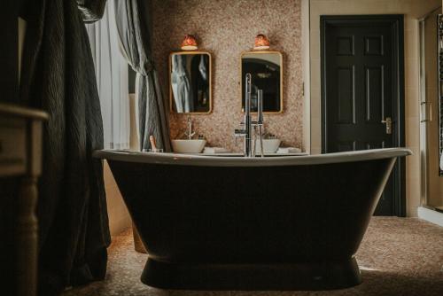 a bath tub in a bathroom with two mirrors at The Croft Hotel in Darlington