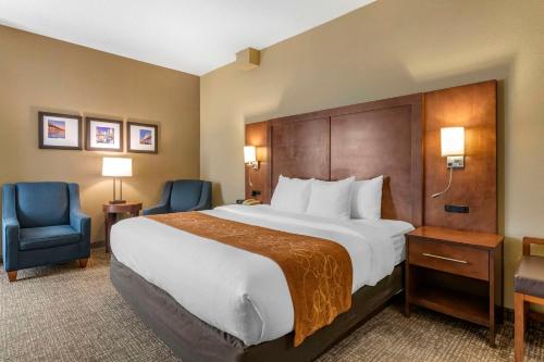 a hotel room with a large bed and two chairs at Comfort Suites Baymeadows Near Butler Blvd in Jacksonville