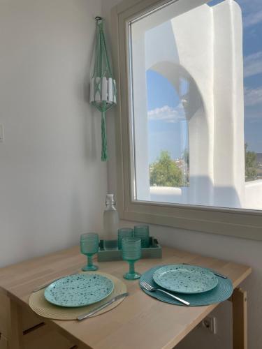 a table with two blue plates and a window at thErοs - Sunset view apartment in Parikia