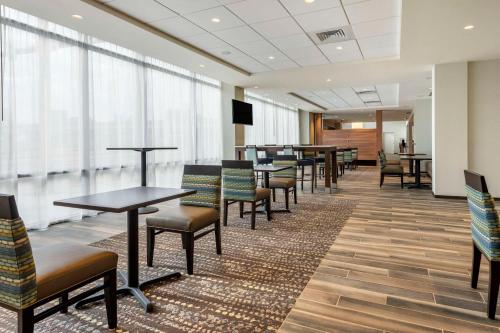 una sala de espera con mesas, sillas y ventanas en Comfort Inn & Suites Pittsburgh-Northshore, en Pittsburgh