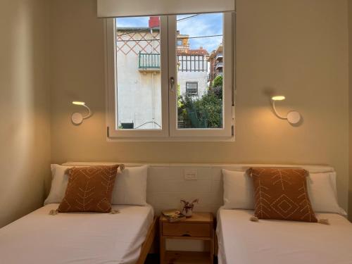 two beds in a room with a window at "Amaluz Ocean Villa" Bilbao Beach para familias y grupos de amigos in Getxo