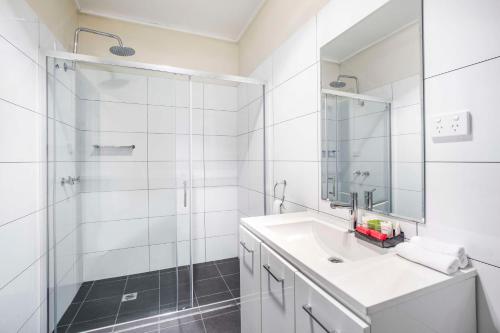 a white bathroom with a shower and a sink at Nightcap at High Flyer Hotel in Bankstown