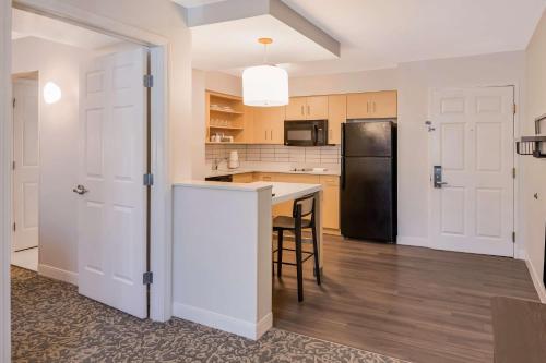 a kitchen with a black refrigerator and a table at Sonesta ES Suites Andover Boston in Andover