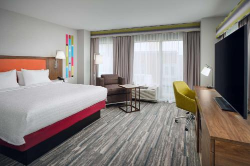 a hotel room with a bed and a desk and a television at Hampton Inn Towson Downtown in Towson