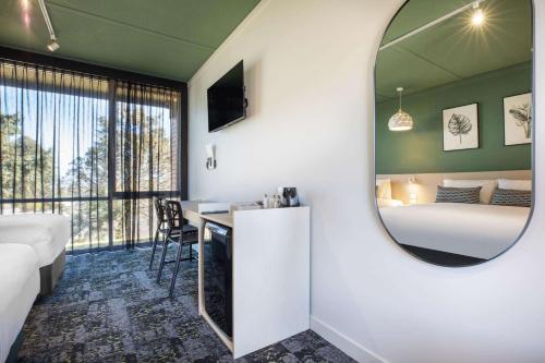 1 dormitorio con espejo, cama y escritorio en Nightcap at Morwell Hotel, en Morwell