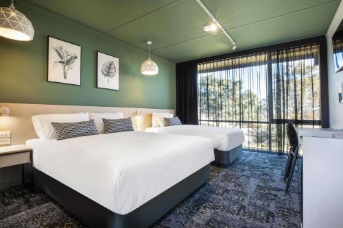 a bedroom with two beds and a large window at Nightcap at Morwell Hotel in Morwell