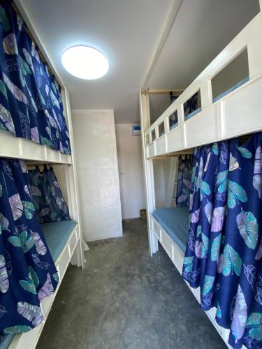 a room with bunk beds with blue curtains at Jambiani Backpackers Hostel in Jambiani
