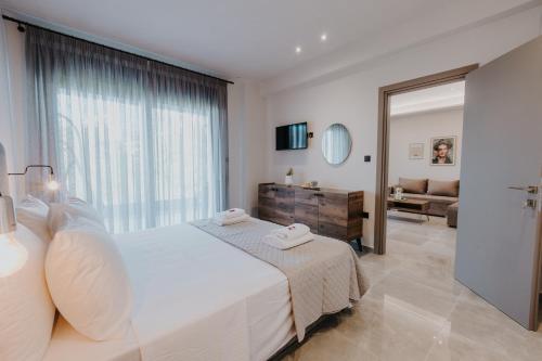 a bedroom with a large white bed and a living room at Pearl Apartel in Volos