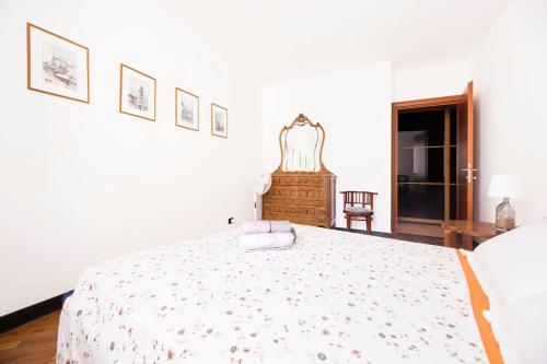 a white bedroom with a large bed and a chair at Prione's Apartment in Genova