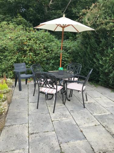 a table and chairs with an umbrella on a patio at Tanglewood Gatwick Bed & Breakfast in Crawley