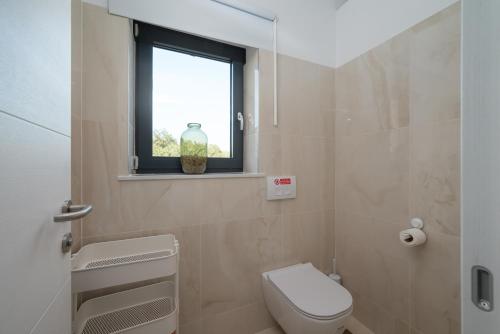 a bathroom with a toilet and a window with a vase at Villa Linnelle seaview- Rovinj, heated pool in Burići