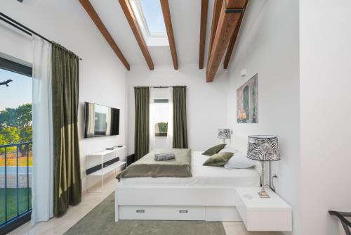 a white bedroom with a bed and a window at Villa Linnelle seaview- Rovinj, heated pool in Burići