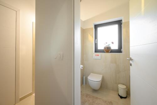 a bathroom with a toilet and a window at Villa Linnelle seaview- Rovinj, heated pool in Burići
