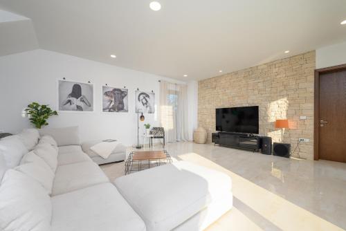 a white living room with a white couch and a tv at Villa Linnelle seaview- Rovinj, heated pool in Burići