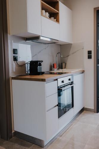 a kitchen with white cabinets and a sink and a stove at Pearl Apartel in Volos