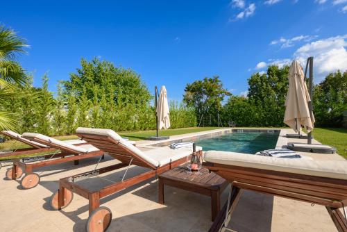 a swimming pool with lounge chairs and umbrellas at Villa Linnelle seaview- Rovinj, heated pool in Burići