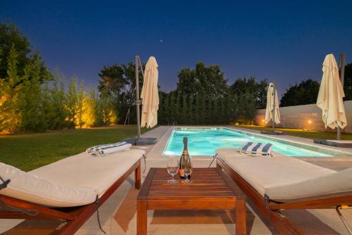 a swimming pool with two beds and a bottle of wine at Villa Linnelle seaview- Rovinj, heated pool in Burići