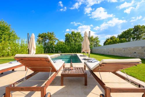 a backyard with a swimming pool and two lawn chairs at Villa Linnelle seaview- Rovinj, heated pool in Burići