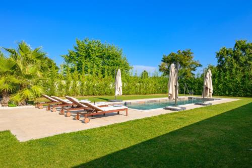a row of lounge chairs and umbrellas next to a pool at Villa Linnelle seaview- Rovinj, heated pool in Burići