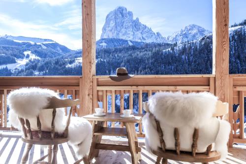 two chairs on a porch with a view of a mountain at Dorfhotel Beludei in Santa Cristina in Val Gardena