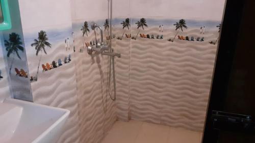 a bathroom with a shower with palm trees on the wall at Tembewadda house in Canacona