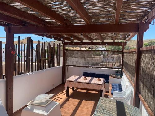 uma pérgola de madeira numa varanda com uma mesa em Casa Mellis Aguamarga em Agua Amarga