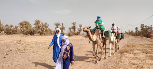 a group of people riding on camels in the desert at Riad Imuhar in Mhamid