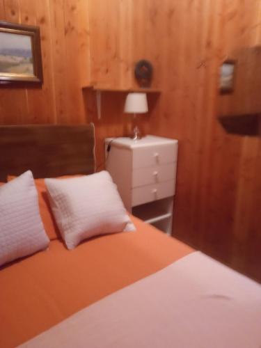ein Schlafzimmer mit einem Bett mit zwei Kissen und einem Nachttisch in der Unterkunft Cabaña Gloria in Coñaripe