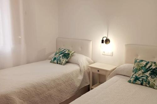 een kleine kamer met 2 bedden en een nachtkastje bij Fernando de Magallanes 15, Bajo en segunda línea de playa in Sanlúcar de Barrameda