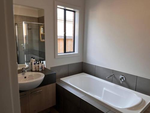 een badkamer met een groot bad en een wastafel bij Spacious 4 bedroom home in Weir Views near Warrawong Estate in Melton