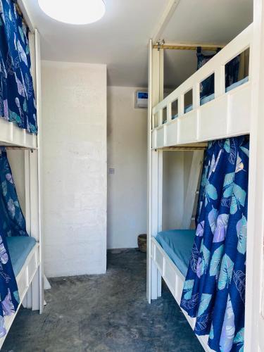a room with two bunk beds with blue sheets at Jambiani Backpackers Hostel in Jambiani