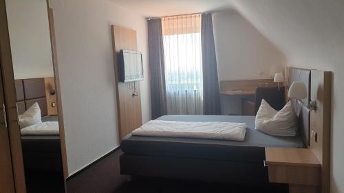 a small bedroom with a bed and a mirror at Restaurant und Hotel Alter Brunnen in Marloffstein