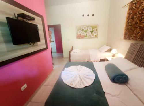 a room with two beds and a flat screen tv at Portal do Sabiá Maresias in Maresias