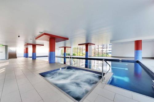 a pool in a building with a hot tub at New Comfy stylish Apt in Rhodes Next to train n shopping center in Sydney