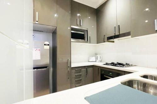 a kitchen with a stainless steel refrigerator and a sink at New Comfy stylish Apt in Rhodes Next to train n shopping center in Sydney